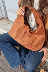Cartera tipo hobo de gamuza negra, con diseño minimalista y asa integrada.