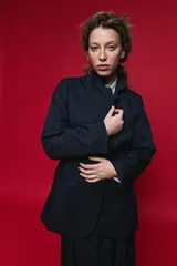 Blazer azul marino con cuello alto y cierre frontal cruzado.