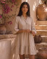 Vestido corto de lino color beige, con cuello mao, escote en V con botones, mangas tres cuartos acampanadas y falda con volados en capas.