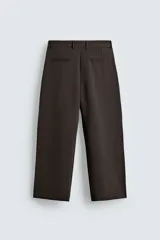 Pantalón de corte relajado con pliegues frontales, bolsillos laterales y bolsillos traseros de vivo. Presenta cierre frontal con cremallera y botón.