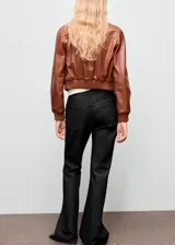 Jeans de tiro medio con diseño flare y lavado oscuro, confeccionados en tejido de algodón estilo tejano vaquero. Cuentan con cinco bolsillos, trabillas para cinturón y cierre frontal con botón y cremallera.