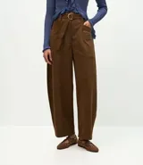 Pantalón de corte barrel con cintura estructurada, trabillas y cinto ajustable con hebilla metálica. Presenta diseño de piernas anchas con recortes laterales y bolsillos frontales.