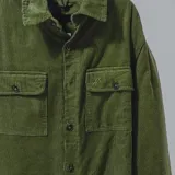 Campera color borgoña de pana con cuello camisero, cierre frontal con botones a presión y dos bolsillos de parche en el pecho. Interior acolchado con patrón de rombos.