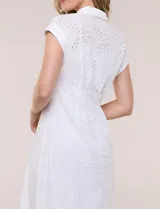Vestido midi blanco estilo camisero de la marca Julia Jordan, confeccionado en tejido broderie 100% algodón. Presenta cuello camisero tradicional, cierre frontal con botones, mangas cortas con vuelta y cintura entallada con pinzas que da paso a una falda evasé. Cuenta con forro interior.