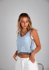 Blusa sin mangas tejida en crochet, color celeste con detalles de bordes en color marrón oscuro. Presenta un diseño de motivos florales geométricos y escote en V.