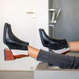 Bota corta de cuero vacuno con diseño tricolor, combinando paneles en negro, blanco y cuero texturizado efecto reptil en tono marrón. Presenta taco cuadrado forrado, punta cuadrada y cierre lateral interno.