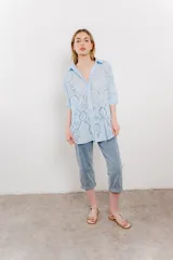 Camisa celeste de algodón liviano con bordado calado tipo broderie, manga larga con puño angosto y botones al frente.