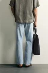 Jeans regular fit de mezclilla negra con efecto lavado, corte recto y tiro medio. Cuenta con diseño de cinco bolsillos y cierre frontal con cremallera y botón.