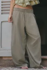 Pantalón fluido de tiro medio color verde militar, con cintura elástica en la parte trasera, pinzas en el delantero y bolsillos laterales ocultos en la costura. Presenta un diseño de pernera ancha y corte tobillero, con cierre frontal de cremallera y botón.