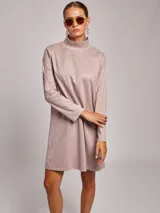 Vestido corto de jersey en color rosado, con cuello subido y mangas largas. Presenta un corte recto y holgado.