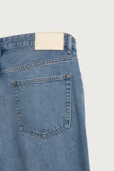 Jeans rectos de tiro medio confeccionados en denim ligero de color azul con efecto lavado. Presentan diseño clásico de cinco bolsillos y cierre frontal con cremallera y botón metálico.