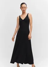 Vestido largo de punto fluido color negro, con escote en V y detalle de nudo en el pecho. Presenta tirantes anchos y diseño evasé con espalda escotada.