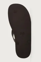 Sandalia de goma color negro, de diseño plano y tiras delgadas en el empeine estilo ojota.