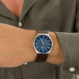 Reloj analógico Skagen modelo Grenen con caja de acero reciclado de 37 mm, esfera azul marino mate con indicadores numéricos y correa de cuero marrón. Cuenta con movimiento solar y resistencia al agua de 3 ATM.