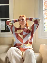 Sweater de punto con diseño geométrico en tonos celeste, marrón y beige.