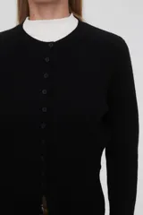 Saco negro de punto, con cuello redondo a la base, manga larga y cierre frontal con botones.