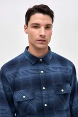 Sobrecamisa de algodón con diseño a cuadros en tonos azules, cuello clásico, cierre frontal con botones y dos bolsillos en el pecho con solapa.