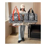 Bolso deportivo de viaje marca Zuomanni, con estampado animal print de leopardo en blanco y negro. Cuenta con doble asa de mano, correa de hombro ajustable y extraíble, y un compartimento inferior independiente con cierre.