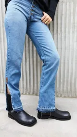 Pantalón de jean celeste de corte recto, con bolsillos delanteros y traseros, y etiqueta de cuero marrón en la parte posterior de la cintura.