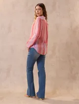 Blusa de gasa estampada con flores en tonos rosa, amarillo y azul. Tiene cuello a la base, escote en V y botones. La delantera tiene detalle plisado y las mangas son 3/4 regulables con presilla y botón.
