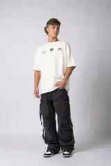 Jean baggy de corte holgado con múltiples bolsillos cargo frontales con cierre metálico. Presenta un acabado lavado, tiro medio y tiras de ajuste en la botamanga.