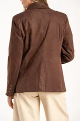 Blazer negro de textura gamuzada con solapas clásicas, cierre frontal de dos botones y bolsillos laterales con solapa.