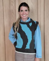 Chaleco tejido de punto con diseño abstracto en bloques de color marrón y turquesa, con cuello redondo y terminaciones acanaladas.