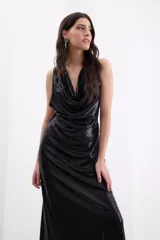 Vestido largo de fiesta color negro, confeccionado en crepe elástico con acabado brillante. Presenta un escote tipo cowl (caído) en el frente, diseño sin mangas y una silueta fluida y elegante.