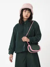 Camisa corta negra de terciopelo, de silueta cuadrada oversized, con bolsillo delantero y detalle en los puños y cuello con botón oro en forma de flor.