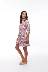 Vestido corto camisero blanco con estampado de motivos campestres en color bordó. Tiene cuello camisero, mangas 3/4, lazo en la cintura y volado en el ruedo.