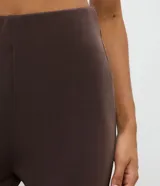 Pantalón deportivo de corte flare, color marrón, con cintura elástica y diseño liso. Presenta una abertura lateral en el bajo.