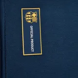 Camiseta de fútbol azul marino con mangas raglán, cierre de cremallera corto en el cuello, escudo del FC Barcelona bordado en el pecho y detalles en azul y rojo en mangas y laterales.