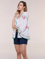 Kimono de poliéster blanco con diseño abierto, mangas amplias y bordados coloridos de motivos florales y arabescos, con terminaciones en ondas de hilo verde.