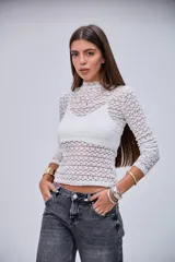 Remera blanca de encaje con diseño texturizado, cuello alto y mangas largas.