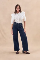 Blusa blanca de algodón con bordado floral, cuello redondo, manga corta con volados y cierre frontal con botones.