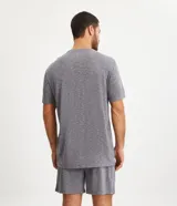 Conjunto de pijama para hombre, compuesto por una remera de manga corta con cuello redondo y un short con cintura elástica y cordón de ajuste. El tejido es de malla flamê con efecto mezcla en tonos beige y marrón.