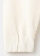 Jersey de piqué color beige, de corte recto con cuello redondo y manga larga.