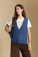 Chaleco tejido color azul, con escote en V, cierre frontal con botones y diseño de líneas verticales en relieve. Presenta terminaciones acanaladas en el ruedo y un borde ondulado en el escote.