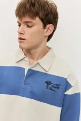 Chomba de friza de manga larga con diseño de rayas horizontales anchas en color beige y azul, cuello polo y pequeño bordado en el pecho.