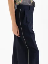 Pantalón sastre color negro de corte recto y tiro alto, confeccionado en mezcla de viscosa y elastano. Presenta bolsillos laterales, presillas para cinto y un delicado vivo decorativo a lo largo de los laterales.