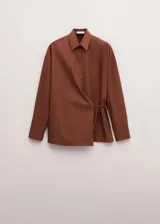 Camisa marrón de algodón con diseño cruzado, cierre lateral con lazo, cuello camisero y manga larga.