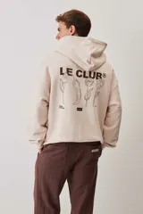 Hoodie de felpa color beige, con capucha, bolsillo frontal tipo canguro y pequeño logo de la marca estampado en el pecho.