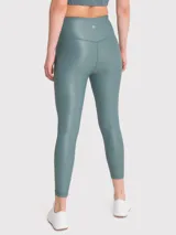 Calza deportiva color verde azulado, tiro alto, sin bolsillos y tela brillante.