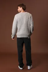 Sweater de punto color gris claro, con cuello redondo y diseño de tejido trenzado.