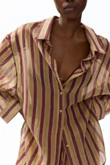 Camisa H&M de corte oversized en mezcla de lyocell, con estampado de rayas verticales en tonos bordó, beige y verde oliva. Presenta cuello camisero, abertura frontal con botones, hombros caídos y mangas largas con puños abotonados.
