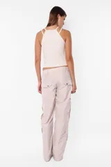 Pantalón cargo negro de corte recto y tiro bajo, con recortes y múltiples bolsillos laterales y traseros con tapa y botón a presión. Cierre frontal con cremallera de nylon y botón personalizado.