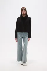 Buzo de cuello alto tipo polera, color verde oliva, con corte holgado, mangas largas y un bolsillo frontal aplicado en el pecho.