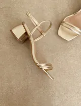Sandalias doradas de fiesta con tiras finas y taco cuadrado bajo.