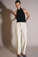Top de cuello halter con escote fluido y caída suave. Presenta cierre con botones en la parte posterior y diseño sin mangas.
