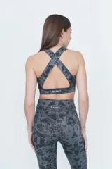 Top deportivo gris con estampado abstracto en negro, espalda cruzada y compresión alta.